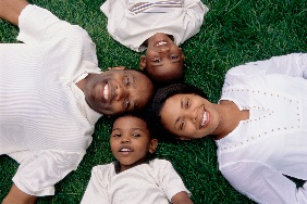 A family laying on the grass looking up