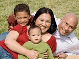 A family together laying on a grass lawn